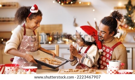 Happy african american family father and children  making cookies on kitchen at christmas time, smiling girl shows her dad and brother xmas gingerbreads   at home during winter holidays