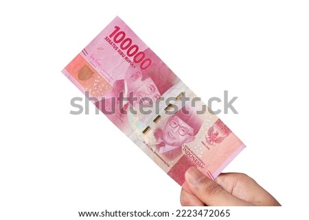 Hand holding one hundred thousand rupiah banknote isolated on a white background. financial concept Royalty-Free Stock Photo #2223472065