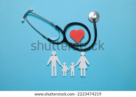 Paper family figures, red heart and stethoscope on light blue background, flat lay. Insurance concept
