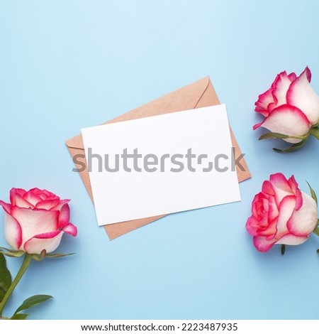 Mockup invitation, blank greeting card and rose flowers. Flat lay, top view.