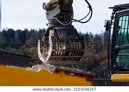 Deconstruction site with tearing down of an apartment building and excavator with claw holding debris on a sunny autumn day. Photo taken November 7th, 2022, Zurich, Switzerland.