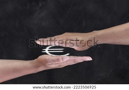 Close-up of female hands on black chalkboard with flattened euro sign drawing in the middle.