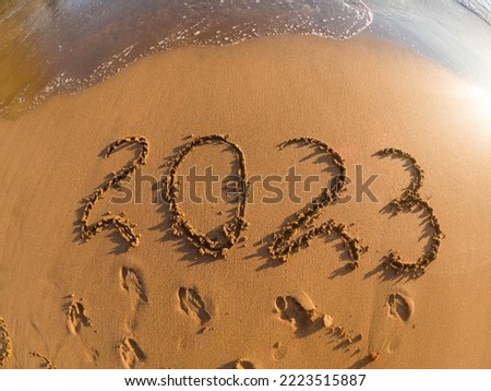 tropical New Year 2023 written in golden sand on the beach