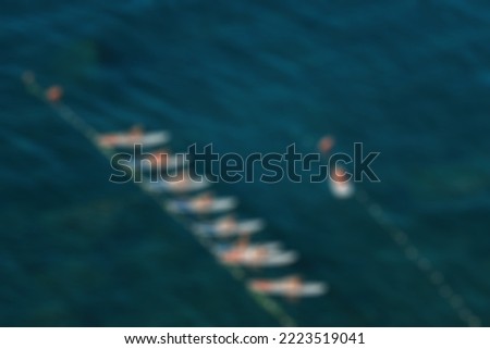 Abstract defocused blured background Group of young womens in swimsuits doing yoga on sup board in calm sea, early morning. Balanced pose - concept of healthy life and natural balance between body and