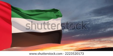 Flag of United Arab Emirates on background of sunset sky. UAE celebration. National day, Flag day, Commemoration day, Martyrs day. Banner with place for text.