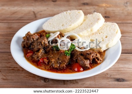 Beef goulash and dumplings (knedliky) on wooden table from Czech Republic Royalty-Free Stock Photo #2223522447