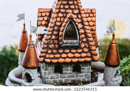 Close-up figurine of a reduced, small ancient palace made of stone, clay in nature in a park, garden. Photography, decor.