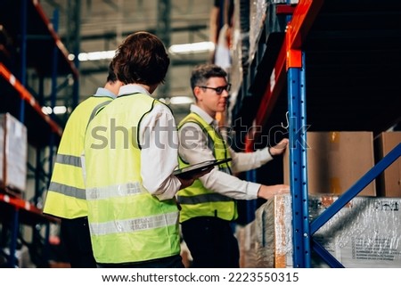 Group of warehouse workers with safety vest talking and discussing plan together, Workers checking and controlling goods working in store factory, Warehouse worker with teamwork concept Royalty-Free Stock Photo #2223550315