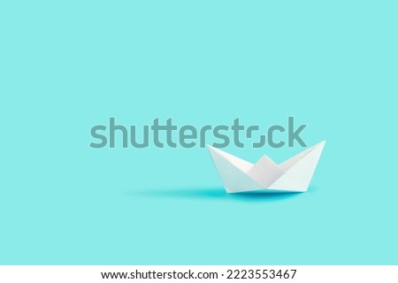 Single paper boat on pastel blue background.
