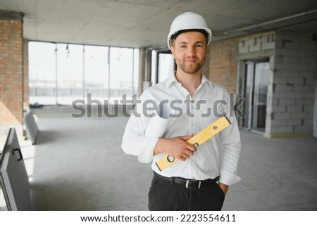 Portrait of an architect builder studying layout plan of the rooms, serious civil engineer working with documents on construction site, building and home renovation, professional foreman at work Royalty-Free Stock Photo #2223554611