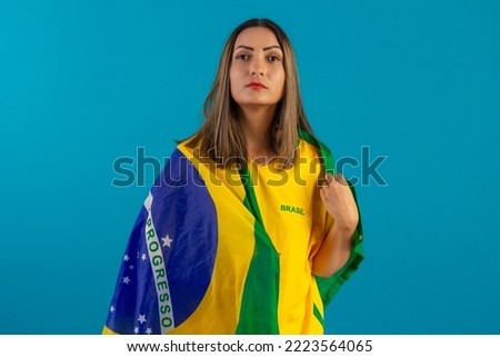 Brazilian female supporter, wearing shirt and Brazilian flag. Brazilian soccer fan in studio photo with blue background and Brazil colors.colored; hair; girl; young
