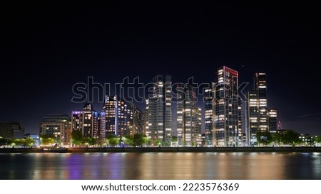 Apartment buildings in London lit up at night and reflected in river thames