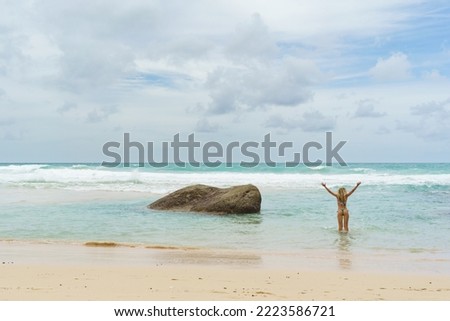 A photo of a young woman looking joyfully out to sea from Kata Beach, Thailand. 