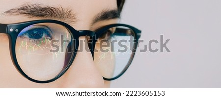 Banner with reflection of the traders market charts in the glasses of a woman looking at a computer monitor on light background. High quality photo