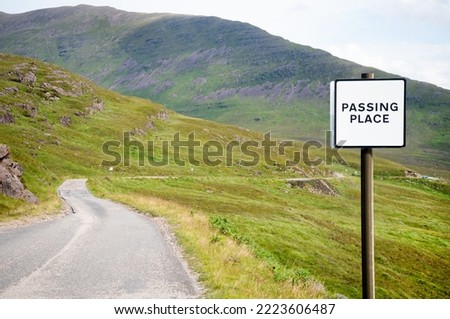 Mountains and narrow highland road stretching beyond,summertime,green grassy glens,passing place,a space at side of road to allow cars and traffic to pass.