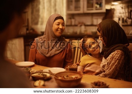 Happy Middle Eastern girl having dinner with extended family in dining room. Royalty-Free Stock Photo #2223608309