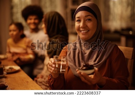 Happy mature Middle Eastern woman celebrating Ramadan with her family and looking at camera. Royalty-Free Stock Photo #2223608337