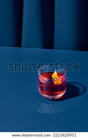 Popular cocktail negroni with gin and vermouth on blue background with shadow. Negroni cocktail on coloured background in trendy style. Contemporary concept with alcohol beverage. Bartender cocktail Royalty-Free Stock Photo #2223620951