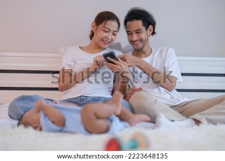 Mom and father use mobile phone enjoy online shopping baby happy laying on bed playing