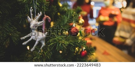 Lovely silver reindeer doll and beautiful ornament ball hang on Christmas tree as Santa decoration for shiny night party at home in winter holiday festival. Add some noise to fit vintage-style image