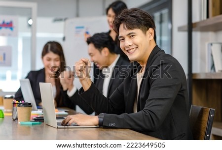 Group of millennial Asian young professional successful male businessmen and female businesswomen in formal suit sitting standing smiling screaming shouting holding fists up celebrating together.