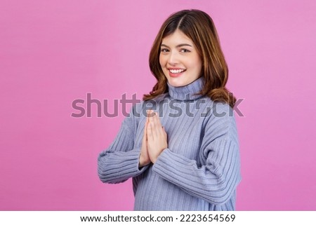 Portrait young happy cheerful woman paying respect, sawasdee symbol from Thailand greeting culture for hello or goodbye and looking at camera isolated pink background. Royalty-Free Stock Photo #2223654569