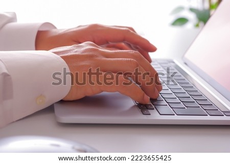 The hand of a man operating a laptop