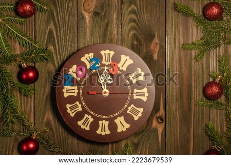 New Year's Eve 2023. Retro-style clock with Christmas decorations on a brown wooden background. The last moments before Christmas or New Year
