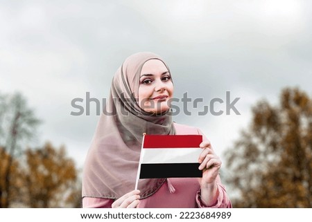Muslim woman in hijab holds flag of Yemen