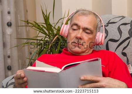 relaxed mature man with headphones and book at home