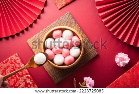 Tang Yuan(sweet dumplings balls), a traditional cuisine for Mid-autumn, Dongzhi (winter solstice ) and Chinese new year with plum flower and tea on red background. Royalty-Free Stock Photo #2223725085