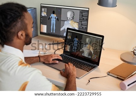 Back view at creative black man building digital 3D models and using multiple computer screens, copy space