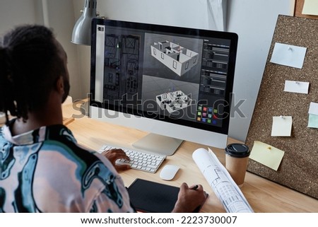 Back view of male digital designer creating 3D architectural model at workplace, copy space