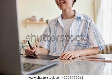 Close up of smiling young woman using pen tablet for digital design at home office workplace, copy space