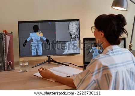 Back view at young female designer building digital 3D models and using computers at workplace Royalty-Free Stock Photo #2223730111
