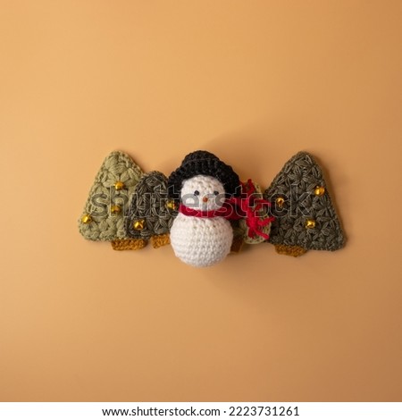 Handmade crochet snowman and  christmas tree on orange pastel background. Merry Christmas and happy new year concept.
