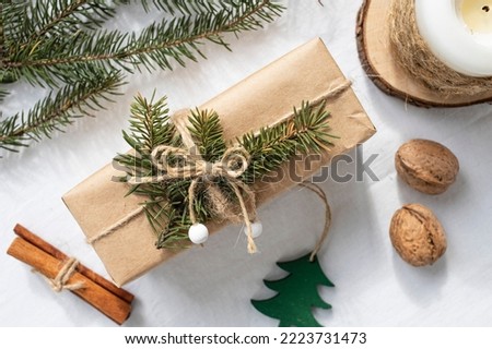A box with a gift made of craft paper and a fir branch on a white background. Christmas composition.