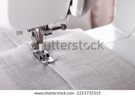 Modern sewing machine presser foot with linen fabric and thread, closeup, copy space. Sewing process clothes, curtains, upholstery. Business, hobby, handmade, zero waste, recycling, repair concept Royalty-Free Stock Photo #2223733319