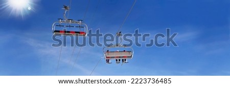  ski lift in blue sky with the sun  in panoramic view  Royalty-Free Stock Photo #2223736485