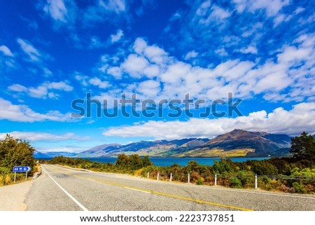 South Island. The beautiful lake Wanaka in New Zealand. Cirrus clouds fly in the sky. Azure lake among the colorful mountains. Asphalt road around the lake. Concept of active and photo tourism