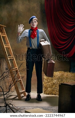 Retro circus show. Vintage portrait of male mime artist expressing sadness and loneliness over dark retro circus backstage background. Concept of emotions, art, fashion, style Royalty-Free Stock Photo #2223744967
