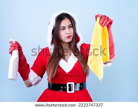 Christmas cleaning. caucasian smiling woman wearing santa clothes and gloves on blue solid background,holding cleaning cloth