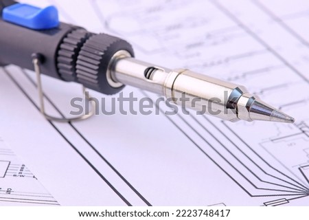 Electric soldering iron close-up on an electronic diagram.Soft focus. Royalty-Free Stock Photo #2223748417