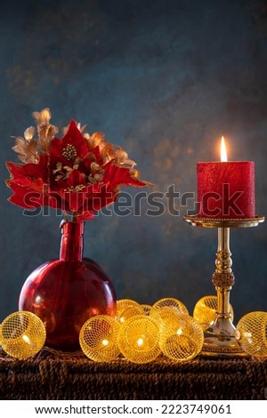 Burning red candle with garlands