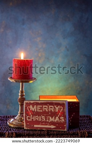 Christmas composition with red candle and gift box on blue background