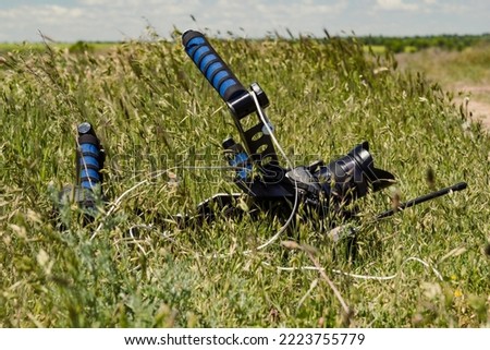 Close up video camera laying in grass concept photo. Meadow. Side view photography with wide plants on background. High quality picture for wallpaper, travel blog, magazine, article
