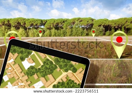 Real estate concept with a vacant land and cadastral parcel available for building construction  near a forest with digital tablet and imaginary cadastral map and city planning Royalty-Free Stock Photo #2223756511