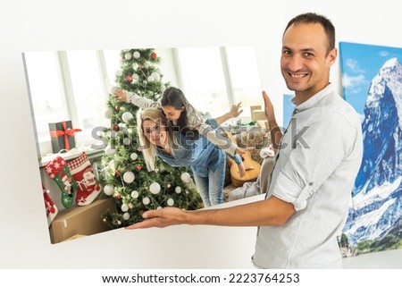 a man holds a Christmas photo on a photo canvas
