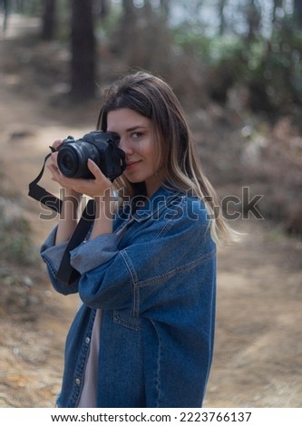 Young beautiful woman taking photograph with camera in forest. Hobby, social life concept.