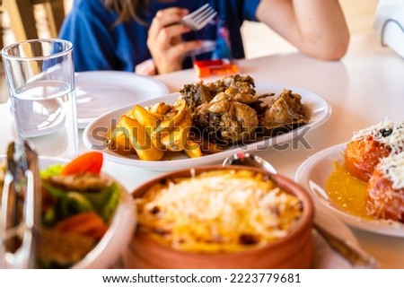 Family eating traditional Greek food in restaurant tavern in Greece. Traditionally served greek food in a greek tavern on authentic dinner tables and traditional plates. Healthy Greek food.